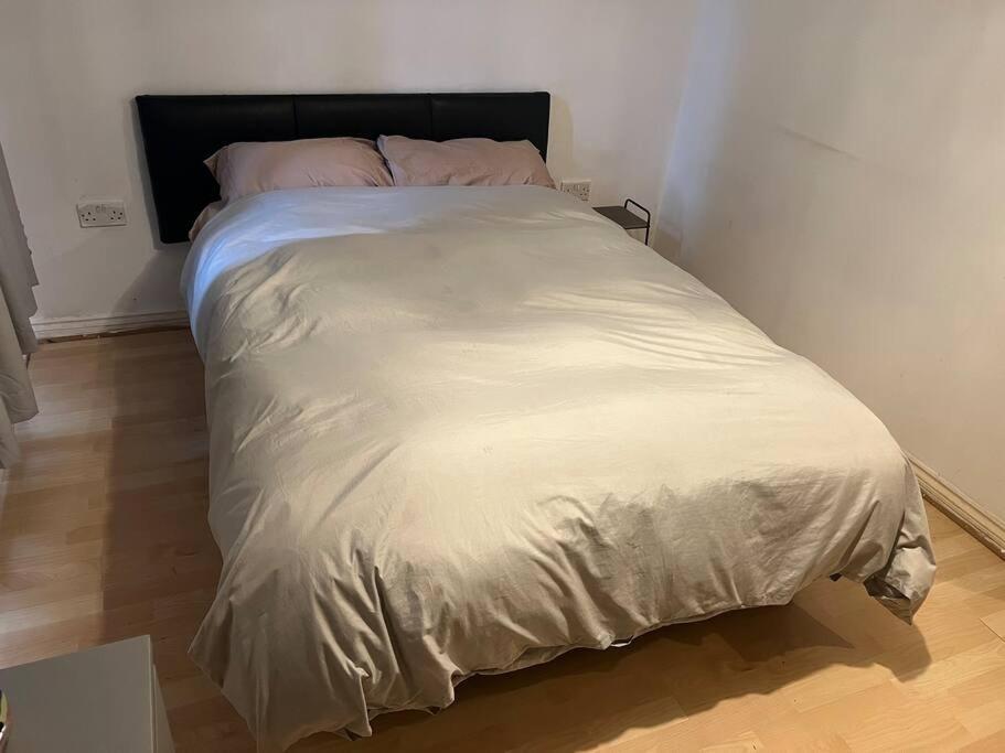 a large white bed in a room with a wooden floor at Quiet and peaceful in Hatfield