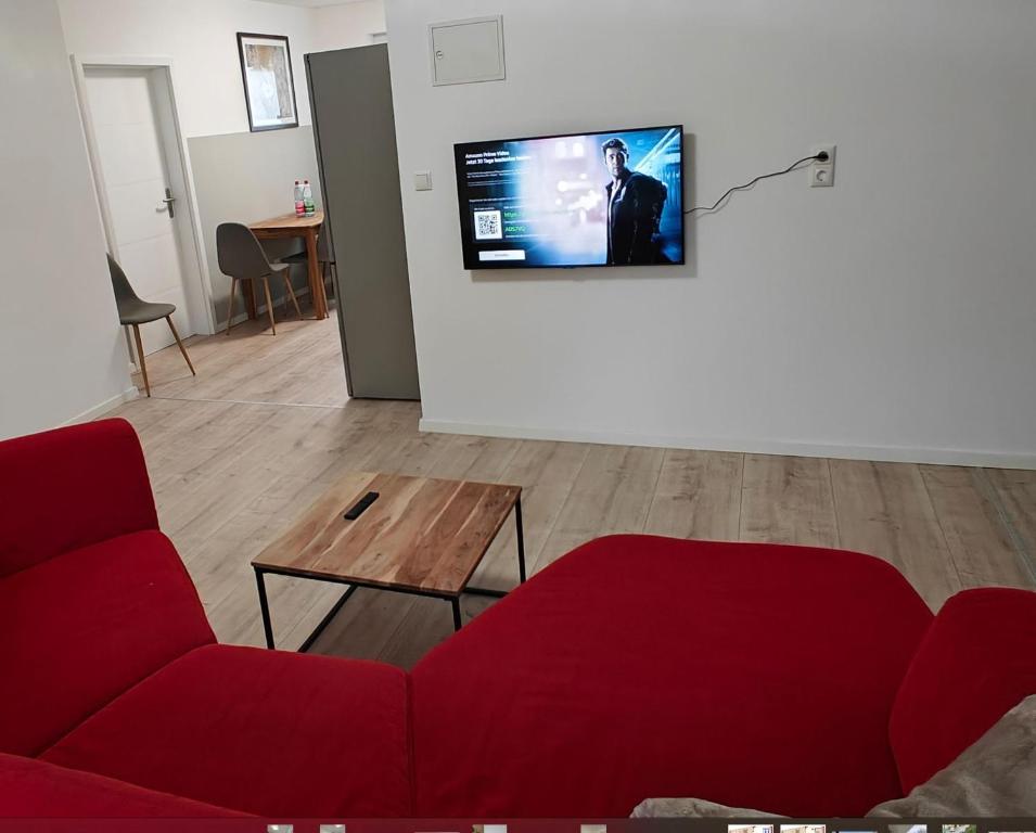 a living room with a red couch and a flat screen tv at Ferienwohnung Sorgenfrei - Parkplatz, Balkon & Terrasse in Coburg