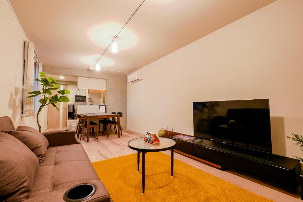een woonkamer met een bank en een grote flatscreen-tv bij Seirai Asakusa Vacation Rental - 3 minutes from station in Tokyo