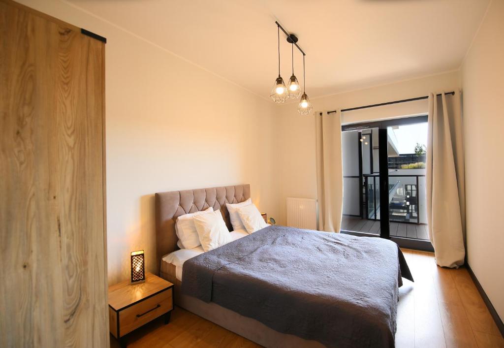 a bedroom with a large bed and a balcony at Apartimento Angel River 7 in Wrocław