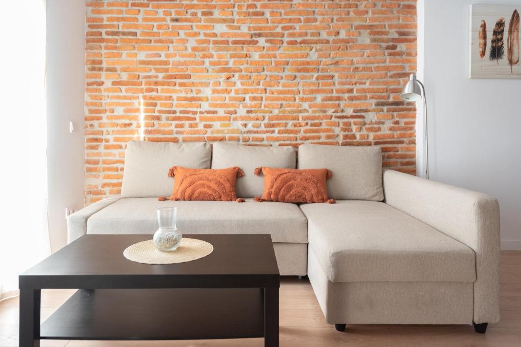 a living room with a couch and a brick wall at Moderno y cómodo apartamento en calle Vargas in Santander