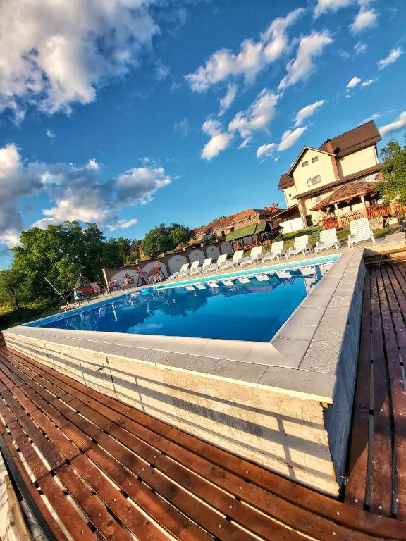 a swimming pool with chairs and a blue sky at Conacul lui Bulică in Novaci-Străini