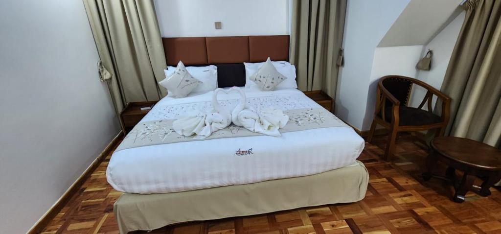 Schlafzimmer mit einem Bett mit weißer Bettwäsche und einem Tisch in der Unterkunft Angani Resorts & Spa Limited in Shamenei