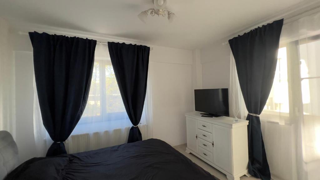 a bedroom with black curtains and a bed and a television at Apartament Craiova Magnolia in Craiova