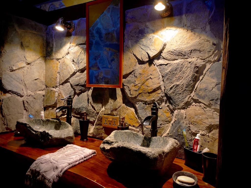 baño con 2 lavabos y pared de piedra en Homestay at "Explore Cafe & Lodge" with stunning ocean view in Chiloe Island, Patagonia, en Duhatao