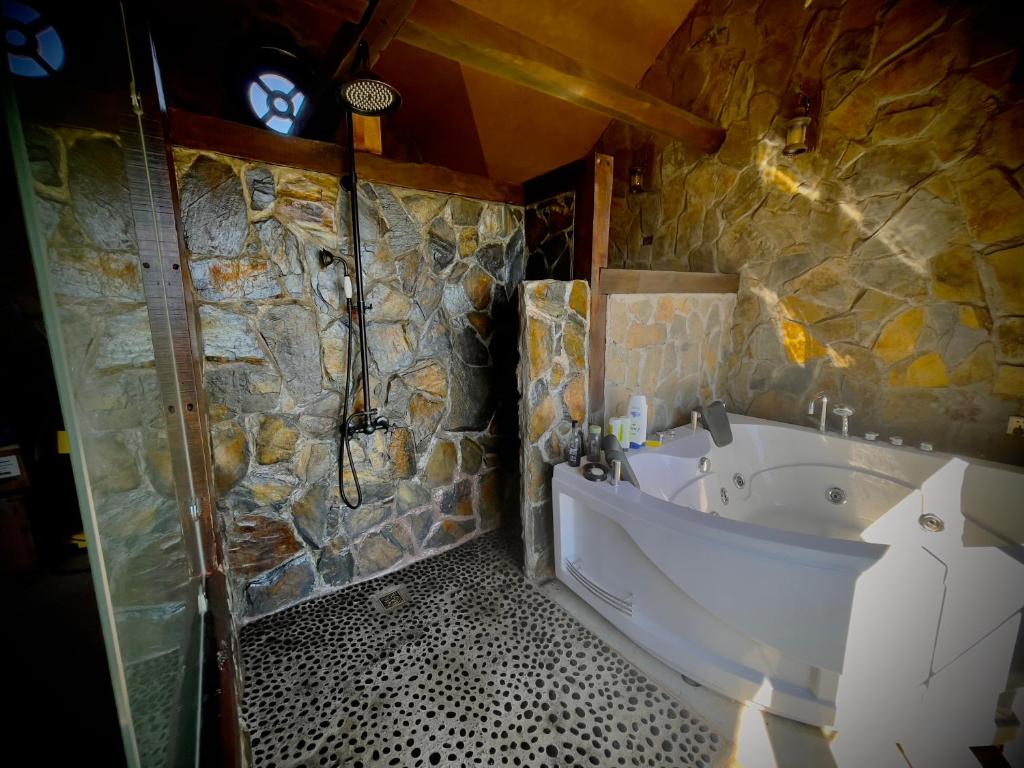 baño con bañera y pared de piedra en Homestay at "Explore Cafe & Lodge" with stunning ocean view in Chiloe Island, Patagonia, en Duhatao
