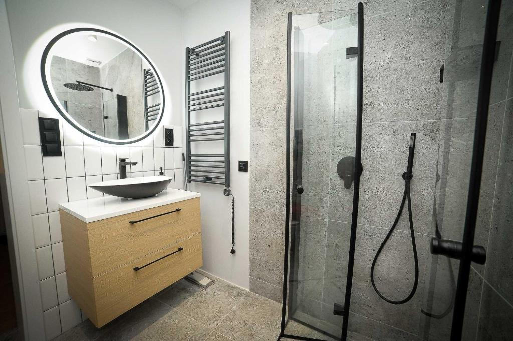 a bathroom with a sink and a shower with a mirror at Apartament Haffnera in Sopot