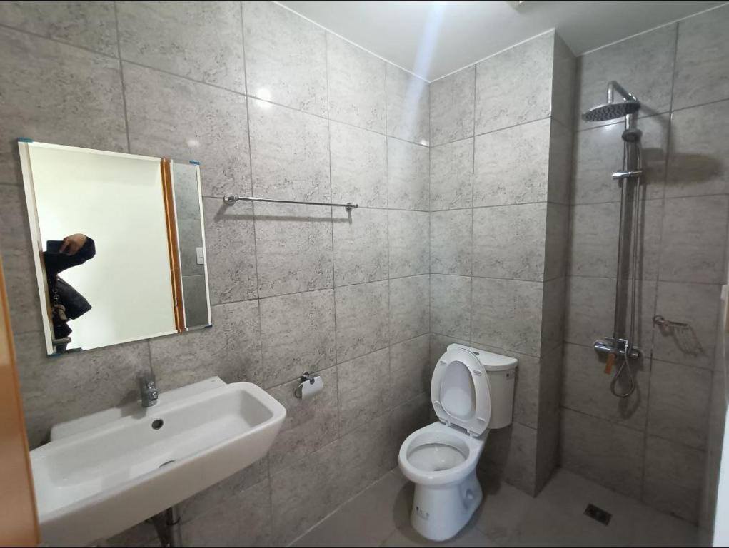 ein Badezimmer mit einem WC, einem Waschbecken und einem Spiegel in der Unterkunft Six Floor Room 624, AMA Tower Residences in Manila