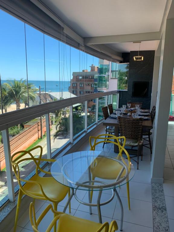 a balcony with tables and chairs and a view of the ocean at BORBOLETAS DO MAR in Bombinhas