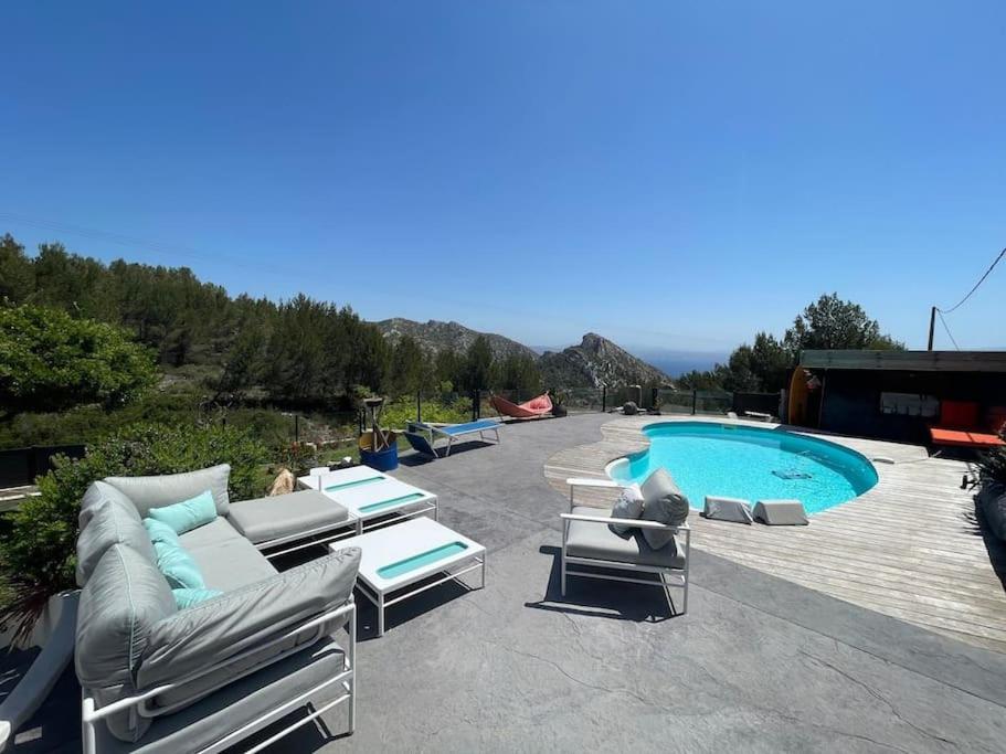 une terrasse avec des chaises longues et une piscine dans l'établissement Villa Caiou/ vue Mer/ Piscine/Jardin, à Le Rove