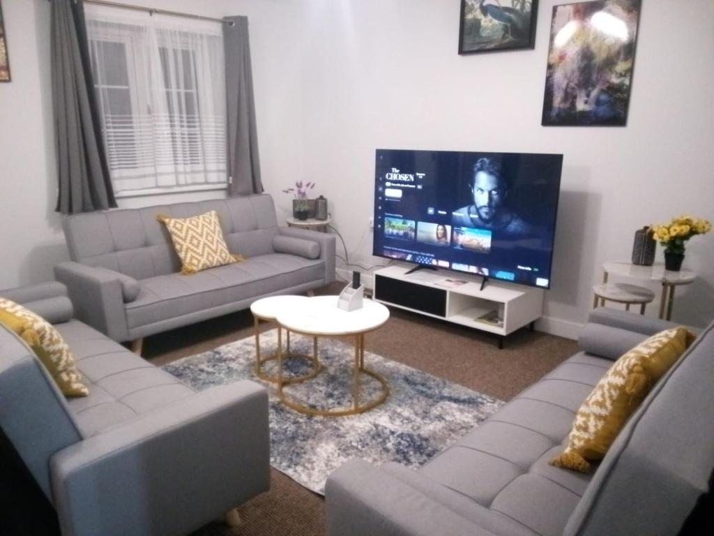un soggiorno con divani e TV a schermo piatto di Cosy & Spacious 4 Bedroom House with Free Parking in Birmingham 