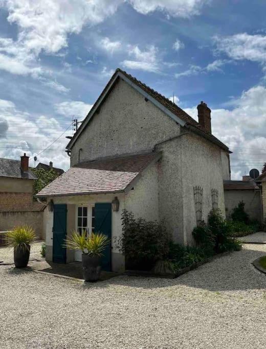 a small white house with a blue door at Maison d'hôtes Au Petit Lavoir in Ymeray