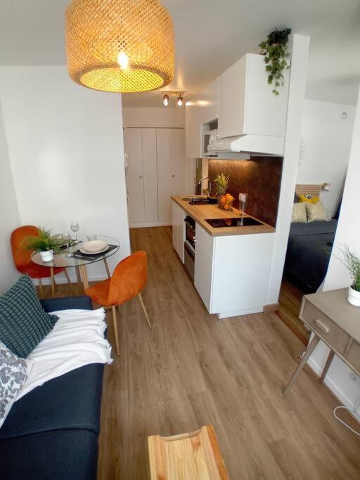 Una sala de estar con un sofá azul y una cocina. en T1bis, balcon, proche Part-Dieu, en Lyon