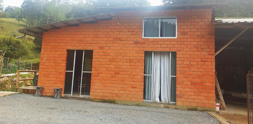 Cette petite maison en briques rouges possède 2 fenêtres. dans l'établissement Sitio do Alemão, à Benedito Novo