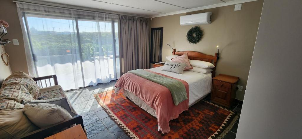 Un dormitorio con una cama y una ventana grande. en Die Huisies, en East London