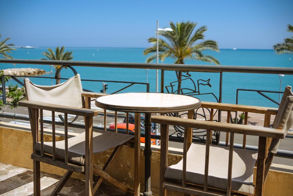 una mesa y sillas en un balcón con vistas al océano en Hôtel du Bord de Mer "Le Vanillé", en Cagnes-sur-Mer