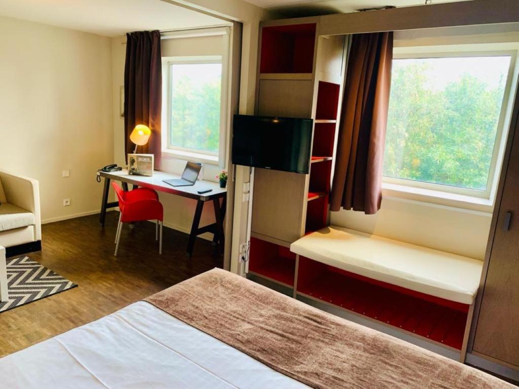Camera con letto e scrivania con computer portatile. di Standing Hotel Suites by Actisource a Roissy en France