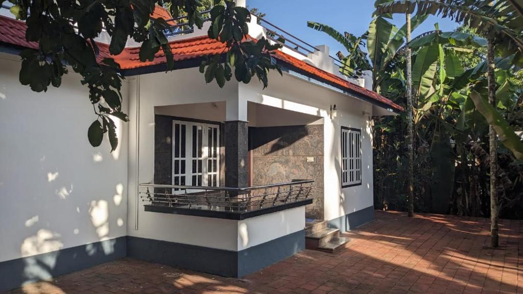 Cette petite maison blanche dispose d'un balcon à l'avant. dans l'établissement Paddy View Service Villa, à Wayanad