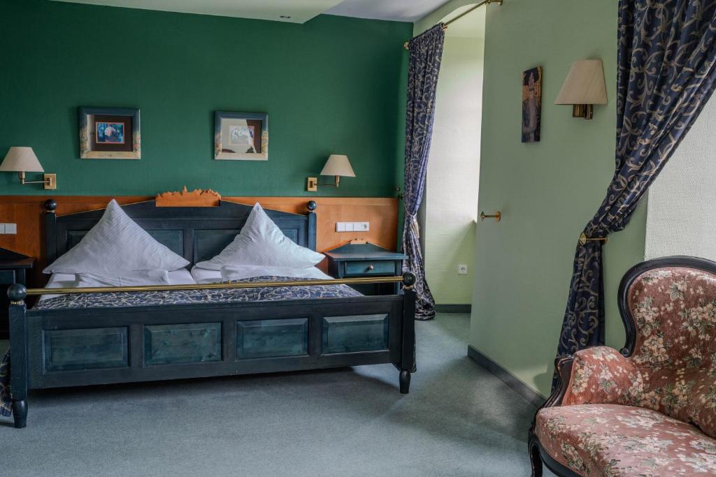 um quarto com uma cama com uma parede verde e uma cadeira em Eventlocation & Hotel Schloss Neuburg em Obrigheim