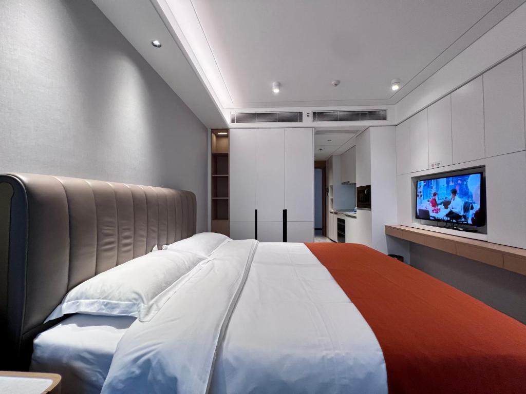 um quarto com uma cama grande e uma televisão de ecrã plano em Kaisen Xiyue Hotel Apartment - Shenzhen International Convention and Exhibition Center em Shenzhen