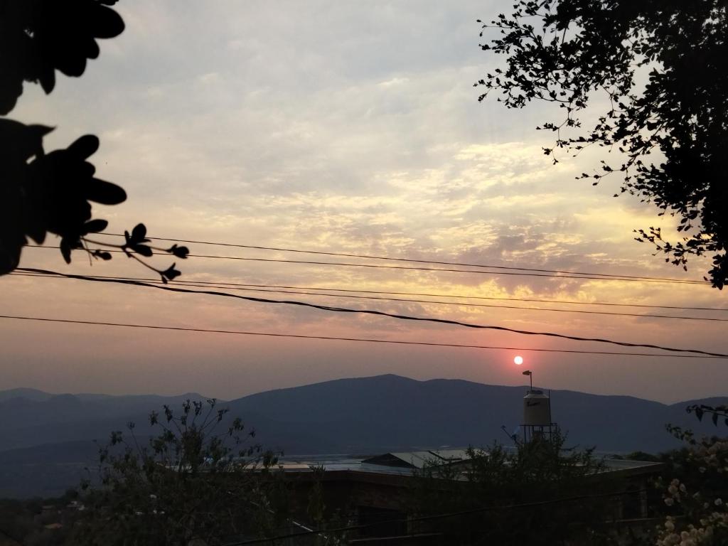 einen Sonnenuntergang mit einem Leuchtturm in der Ferne in der Unterkunft Casa los Olivos in Tepoztlán