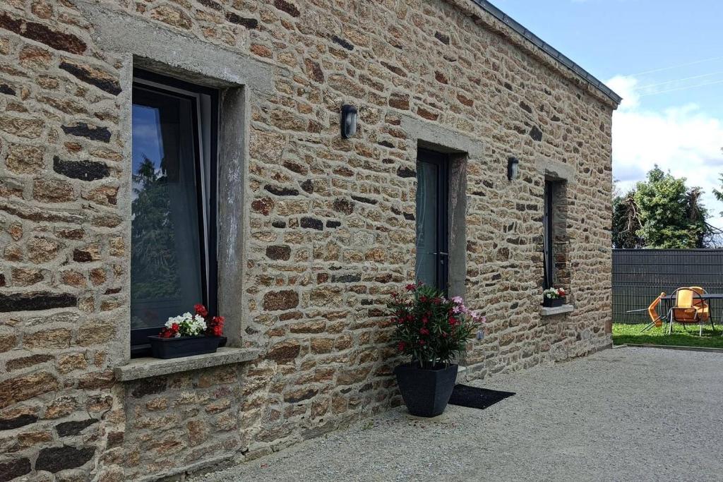ein Backsteingebäude mit zwei Fenstern und zwei Topfpflanzen in der Unterkunft Le Goh Reste, agréable maison de campagne in Locmaria-Grand-Champ