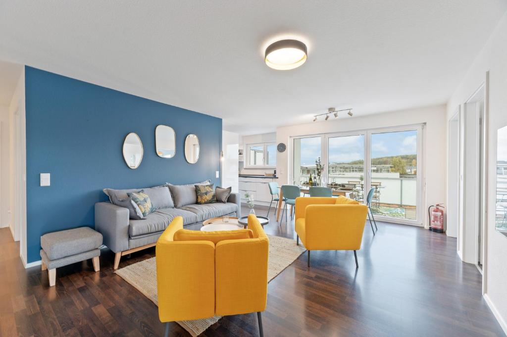 een woonkamer met een bank en gele stoelen bij Design-Apartment - Küche - Dachterrasse - zentral in Leinfelden-Echterdingen