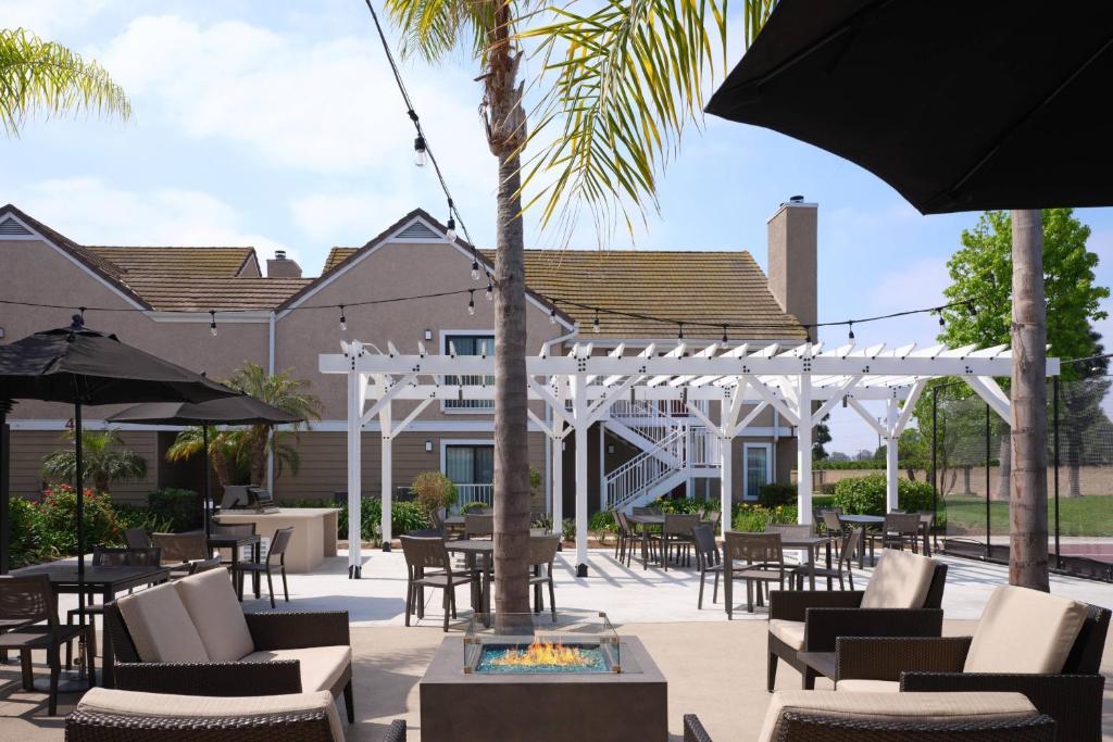 un patio con sillas, mesas y sombrillas en Residence Inn Costa Mesa Newport Beach, en Costa Mesa