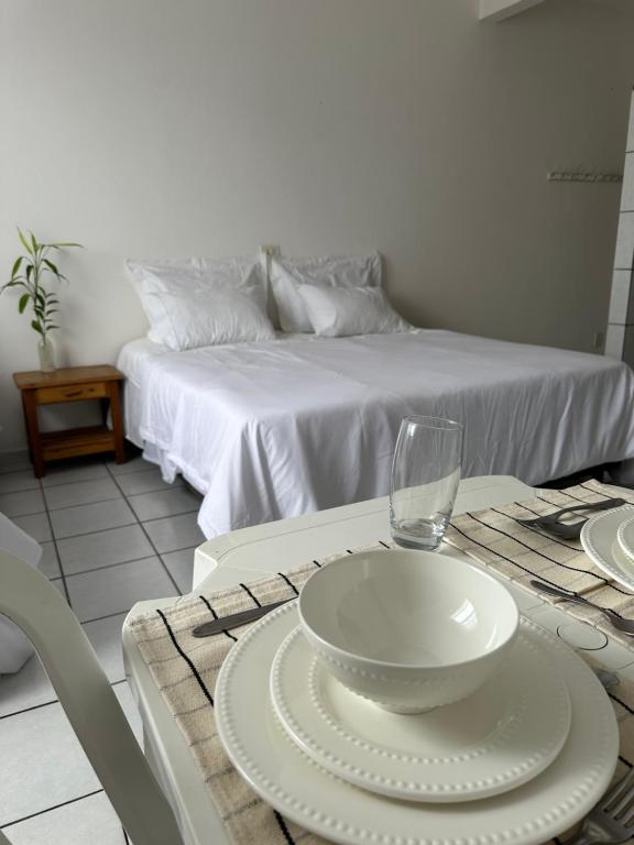 una mesa con un plato blanco y un vaso en ella en Residencial Castelinho, en Mucuri