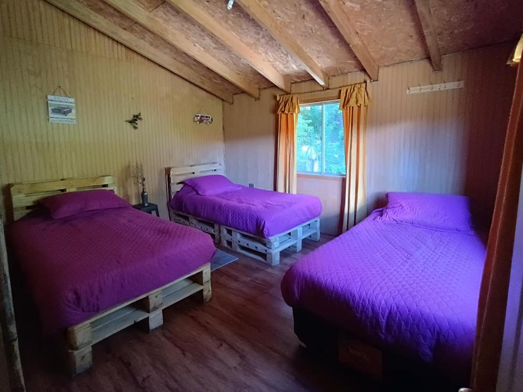 2 camas en una habitación con mantas moradas en Petrohue hospedaje Dónde la Nena, en Petrohué