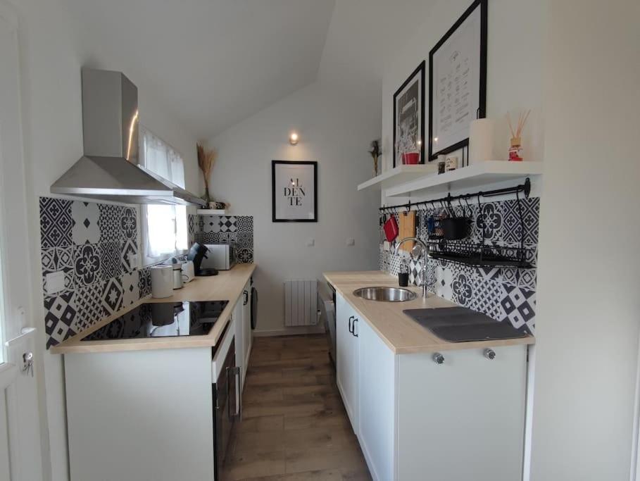 eine Küche mit weißen Schränken und schwarzen und weißen Fliesen in der Unterkunft Home Sweet Somme in Arry