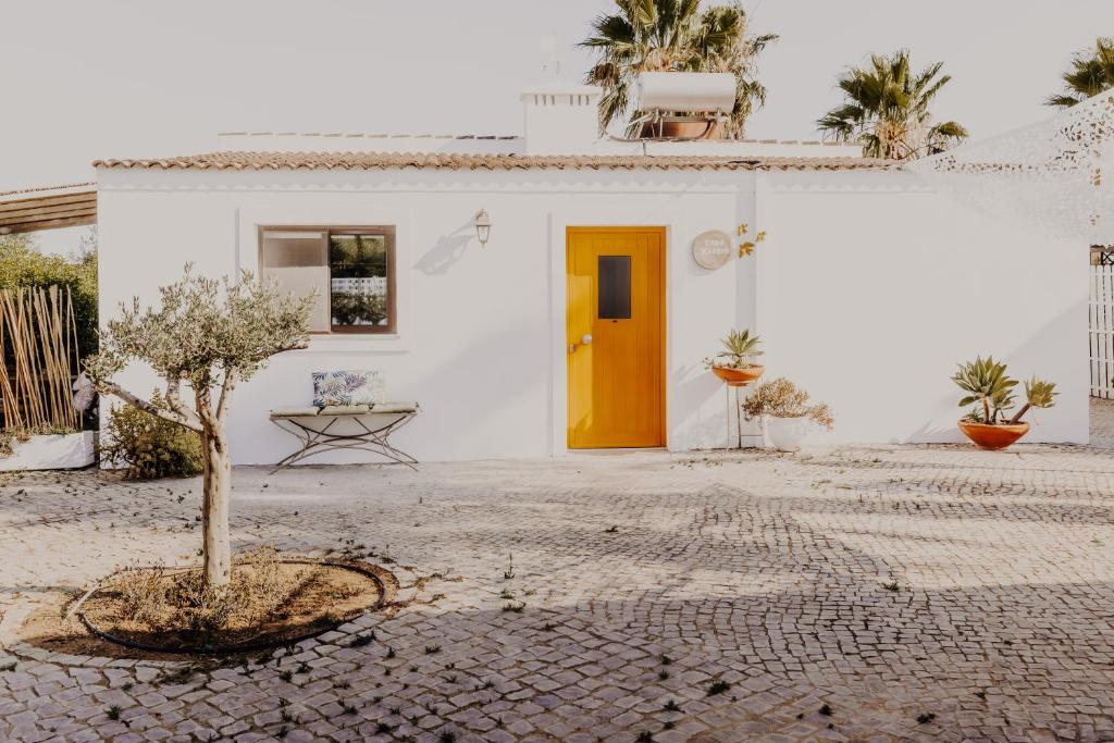 ファロにあるCasa Xarém - Vinhas de Nexeの黄色い扉と木のある白い家