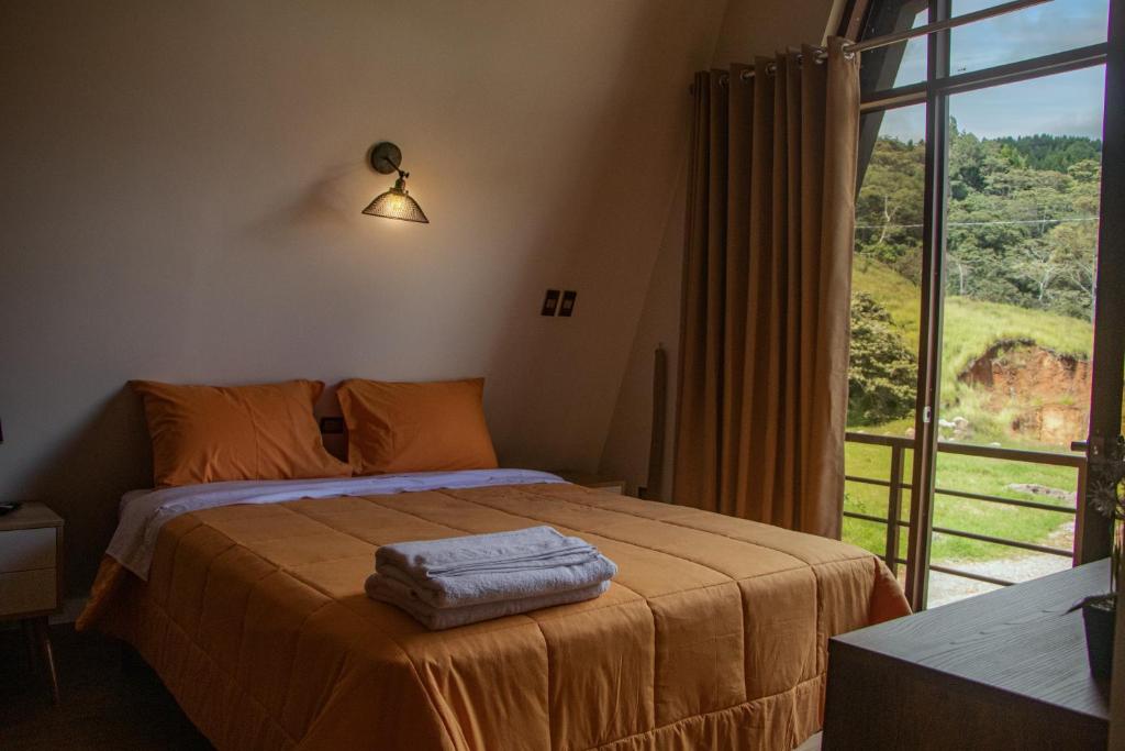 a bedroom with a bed and a large window at Habitaciones Alpes Oxapampa in Oxapampa