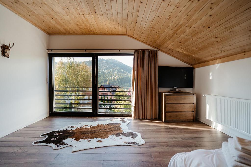 ein Schlafzimmer mit einem großen Fenster und einem TV in der Unterkunft Green Garden in Băile Borşa