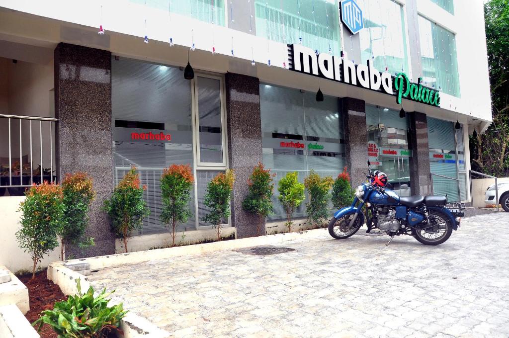 Una motocicleta azul estacionada frente a un edificio en MARHABA PALACE en Kozhikode