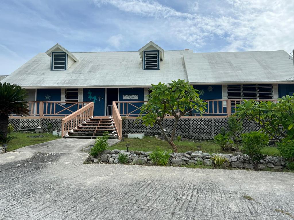 a blue house with a staircase in front of it at Turtles Nest Bahamas in Hermitage