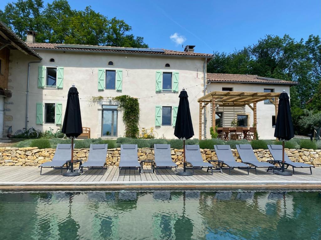 塞普的住宿－La Maison des 3 Chouettes，一组椅子和遮阳伞,位于游泳池旁