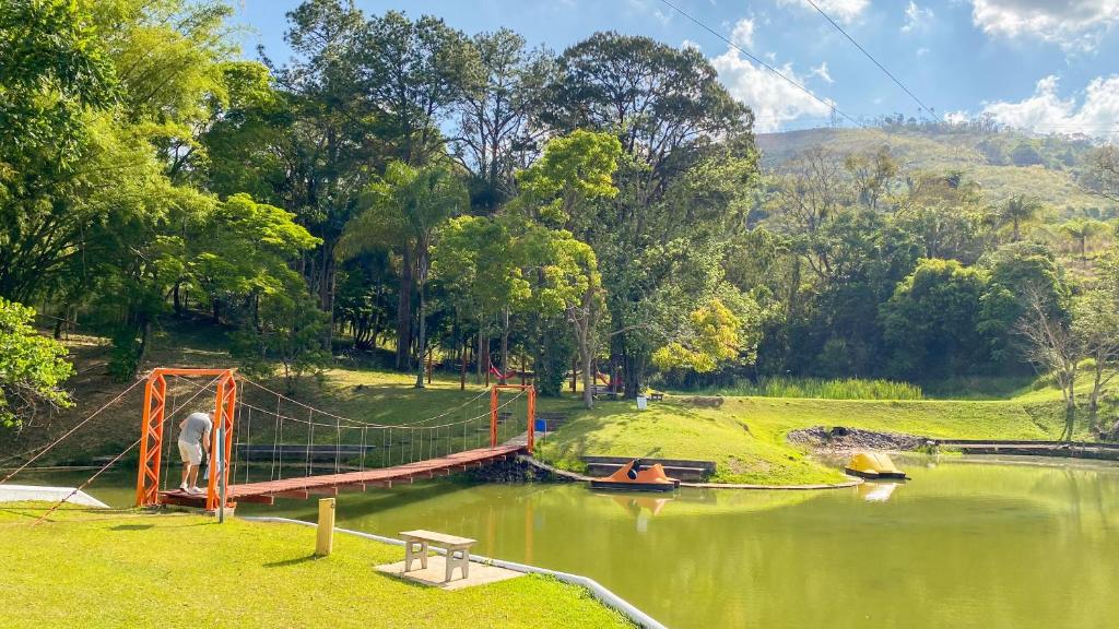 a bridge over a river with two people in a boat at O Recanto Pousada in Serra Negra