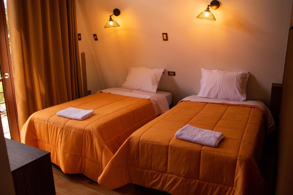 two beds in a hotel room with towels on them at Habitación Alpes doble independiente in Oxapampa
