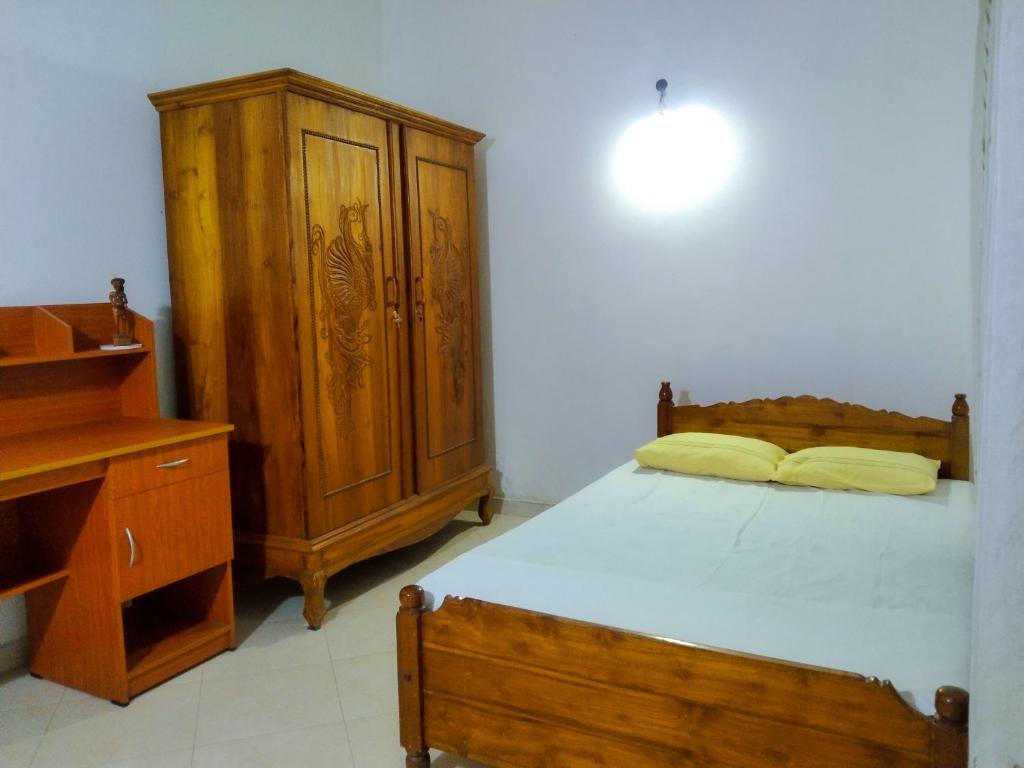 um quarto com uma cama e um armário de madeira em Villa Charumathi em Matara