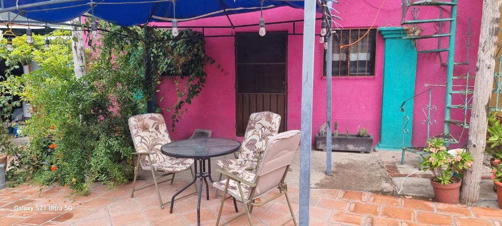 une table et des chaises devant une maison rose dans l'établissement Casa teocalli, à Teotitlán del Valle