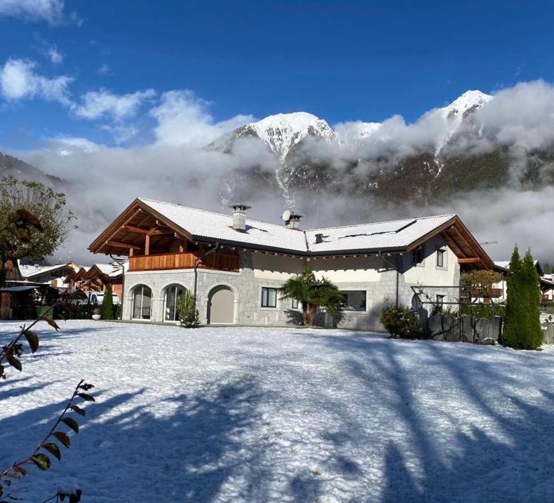 a house in the snow with a snow covered mountain at B&B Casa il sasso in Pinzolo