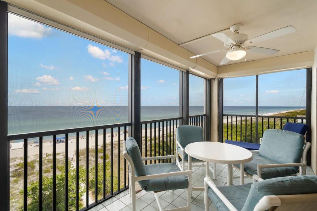a balcony with a table and chairs and the ocean at Beachfront Condo with Pool and Hot Tub Reflections On The Gulf 504 in Clearwater Beach