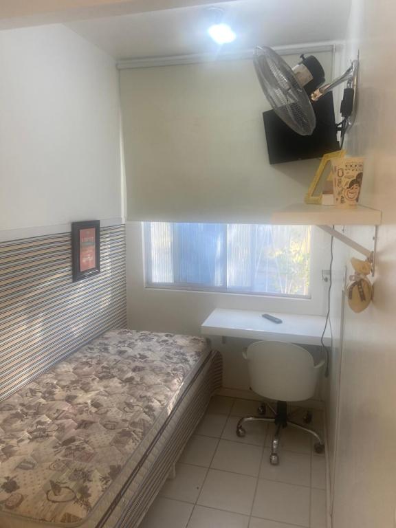 um pequeno quarto com uma cama, uma secretária e uma janela em República Descolada em Florianópolis