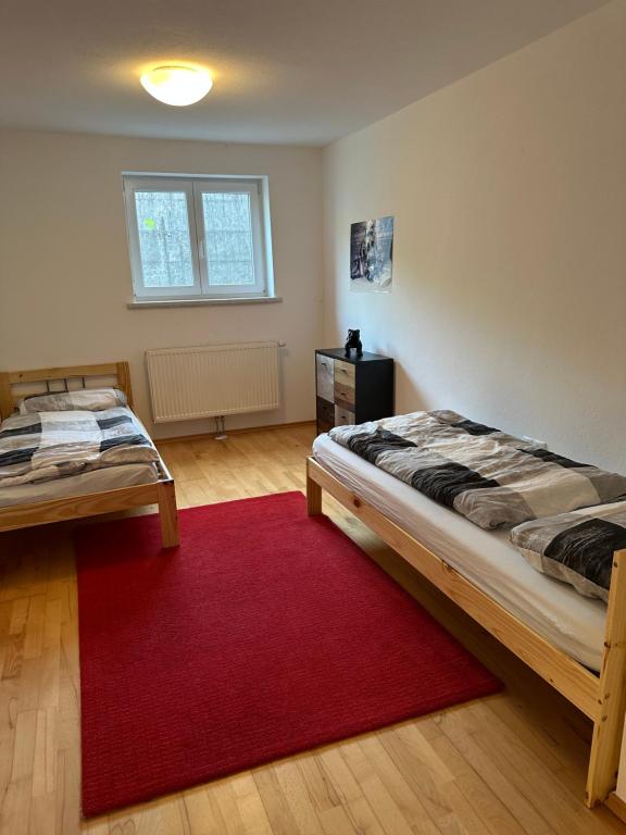 a bedroom with two beds and a red rug at Urlaub mit Hund im Salzburger Land in Wegscheid