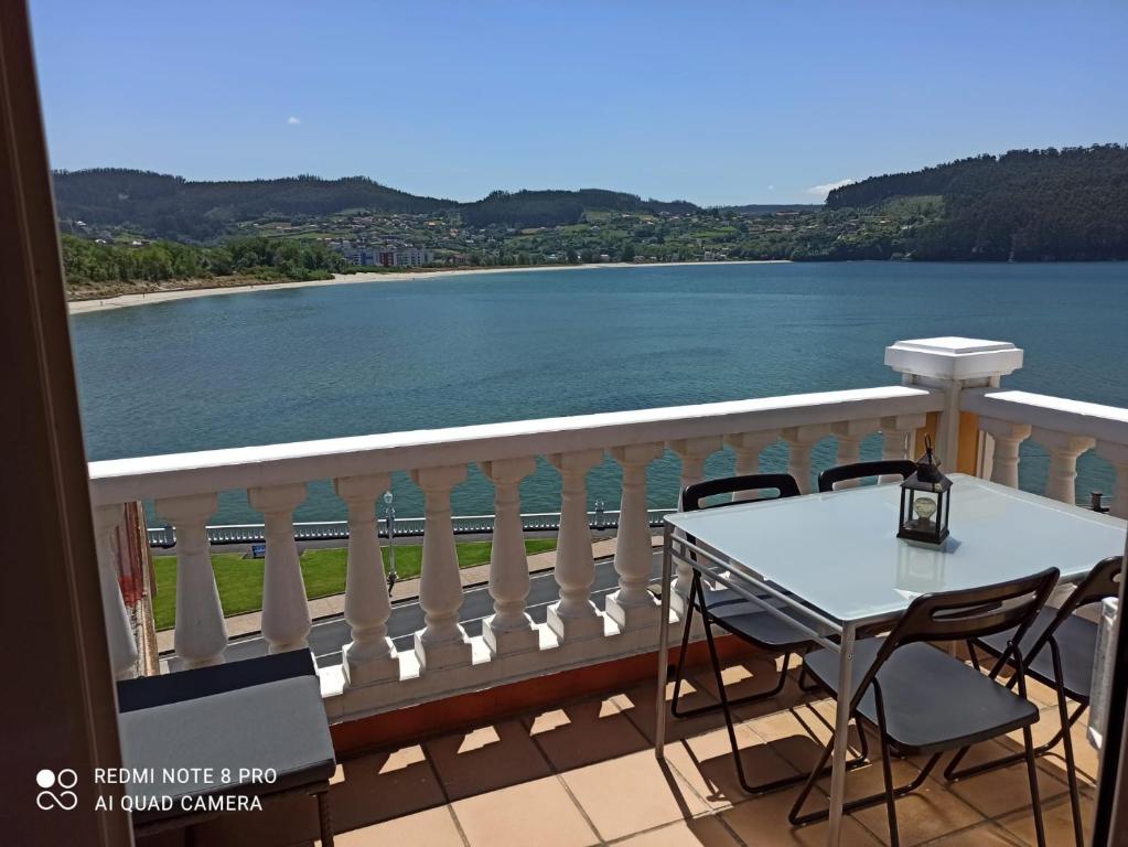 una mesa y sillas en un balcón con vistas al agua en Casa da Costa - Piso con galería y terraza con vistas al mar en Cedeira