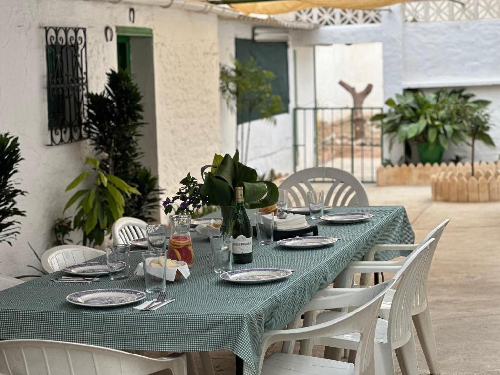 ein Tisch mit grüner Tischdecke und weißen Stühlen in der Unterkunft Villa Remedios in Torremolinos