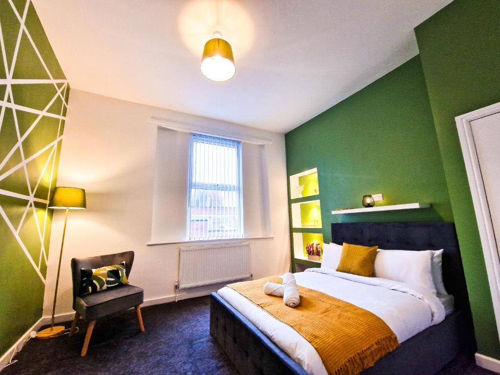 a bedroom with green walls and a bed and a chair at Modern 2 bedroom flat County Rd in Liverpool