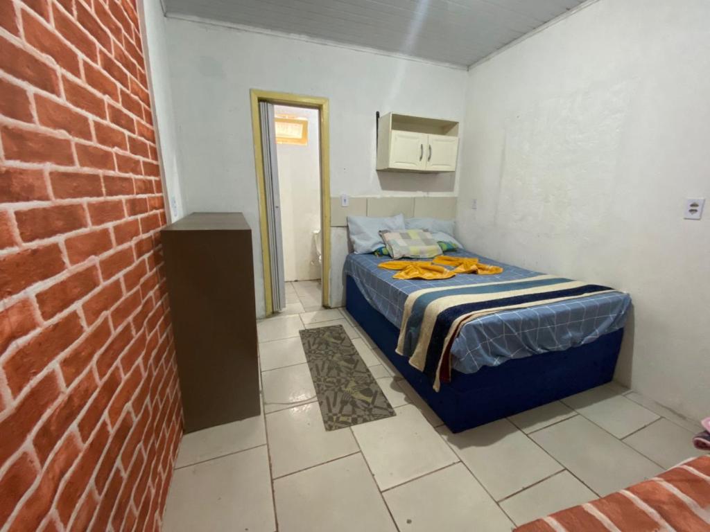 een kleine slaapkamer met een bed en een bakstenen muur bij Itajai Quartos e Suites in Itajaí