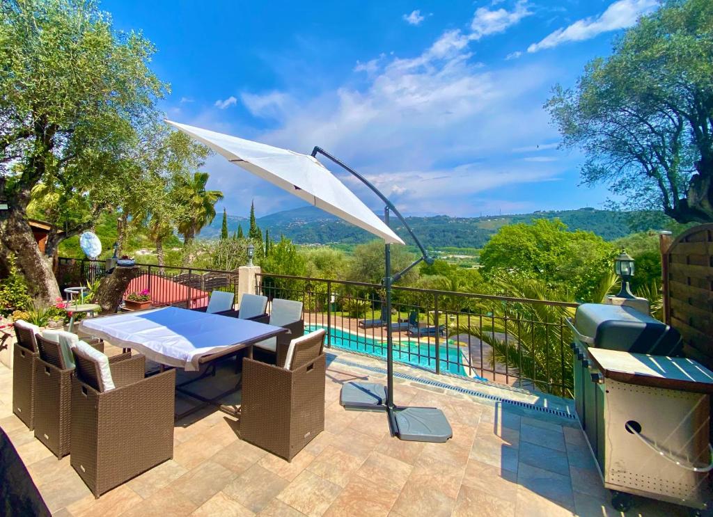 un patio con mesa, sombrilla y piscina en Canarias Bungalow, en Saint-Jeannet